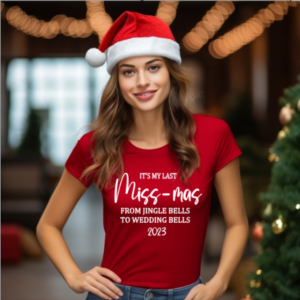 Woman wearing a santa hat and a red t-shirt with the wording 'It's my last Miss-mas from jingle bells to wedding bells 2025, printed in white.